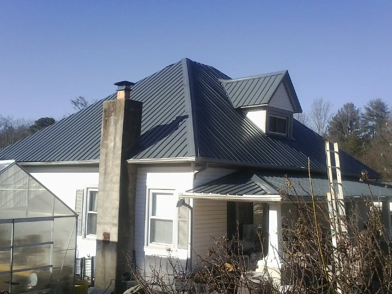 Dark blue standing seam metal roof on a white farmhouse with dormer — Slate & Tile Roof Repair by Roofing Brothers in Hillsborough