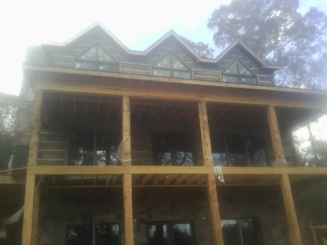 Dormers and porch framing on a large log home under construction — Roof Coating work by our crew in Hillsborough